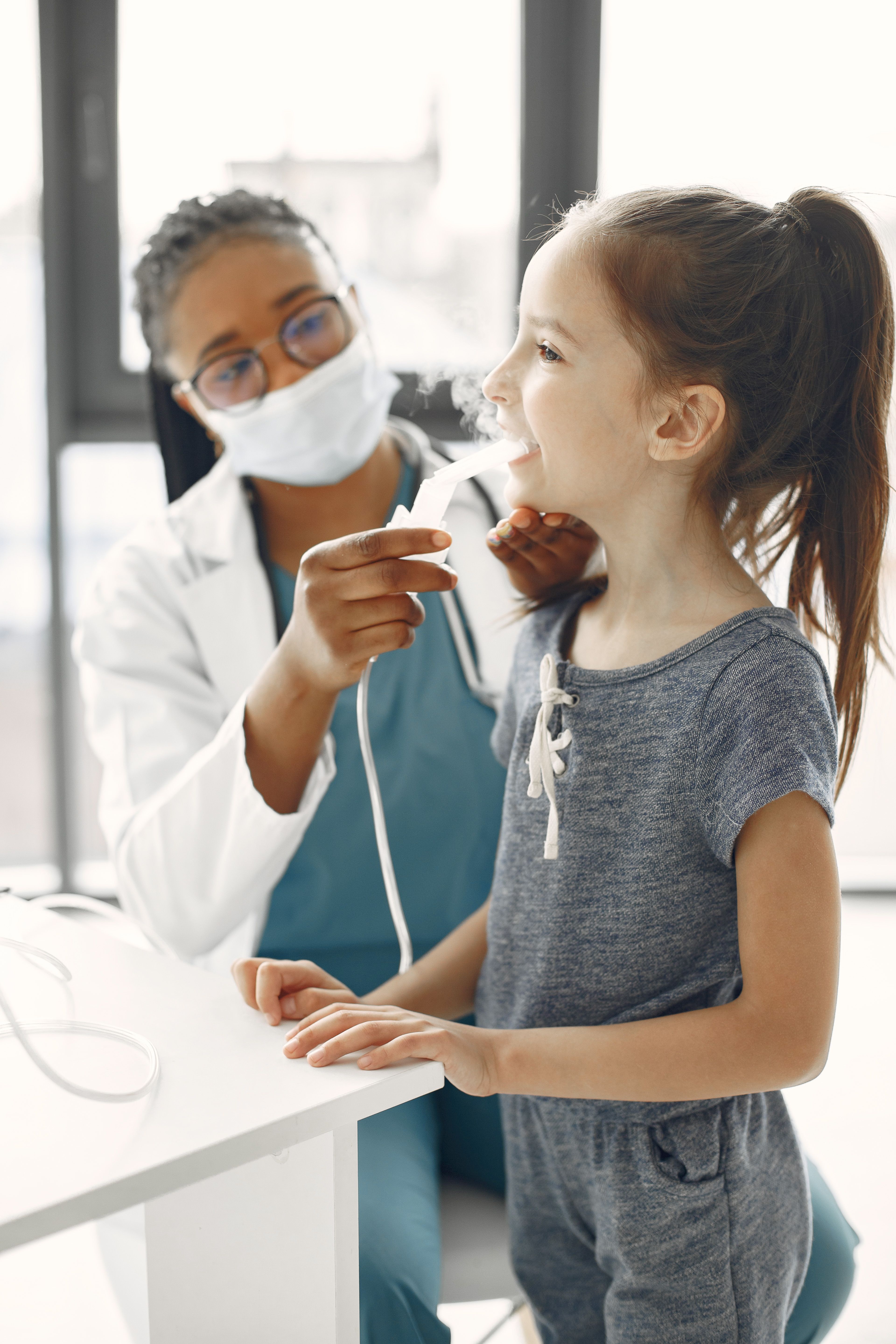 A clinician helping a young patient use a nebulizer